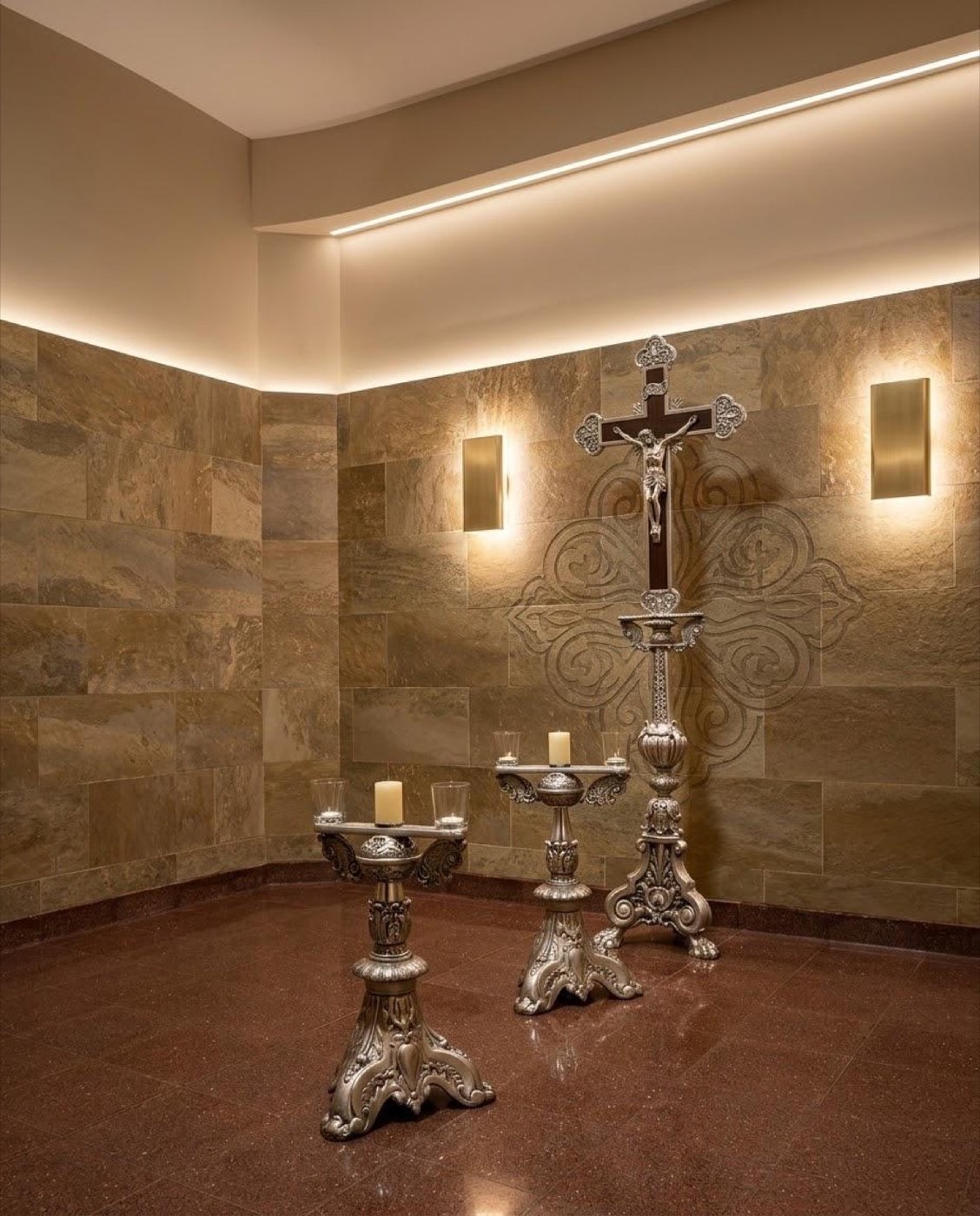Capilla revestida en piedra travertino, con crucifijo y candelabros