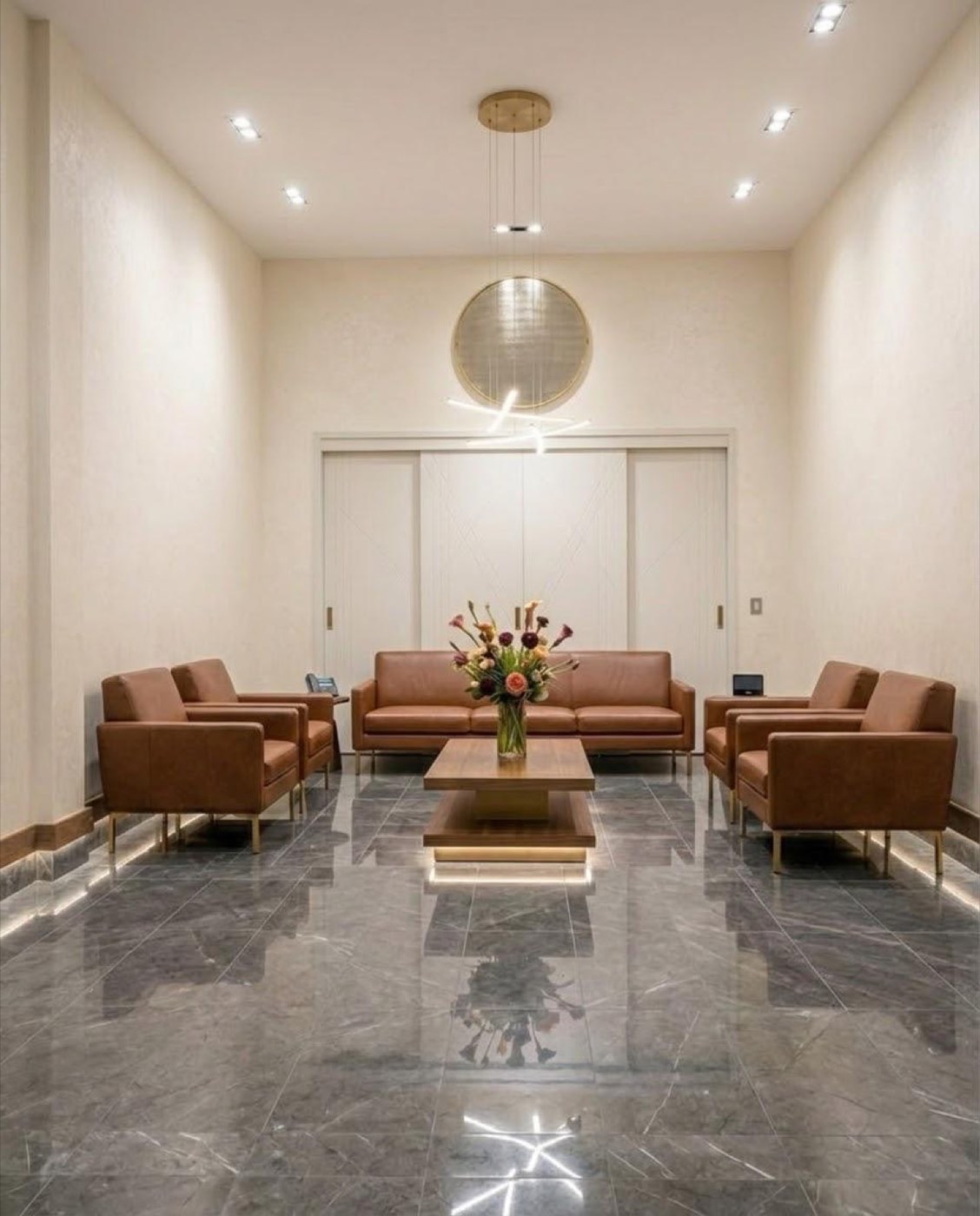 Living con sillones de cuero cognac y espejo circular de bronce