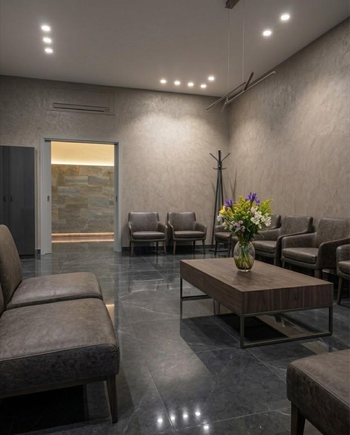 Sala de espera con sillones de cuero gris y piso de mármol